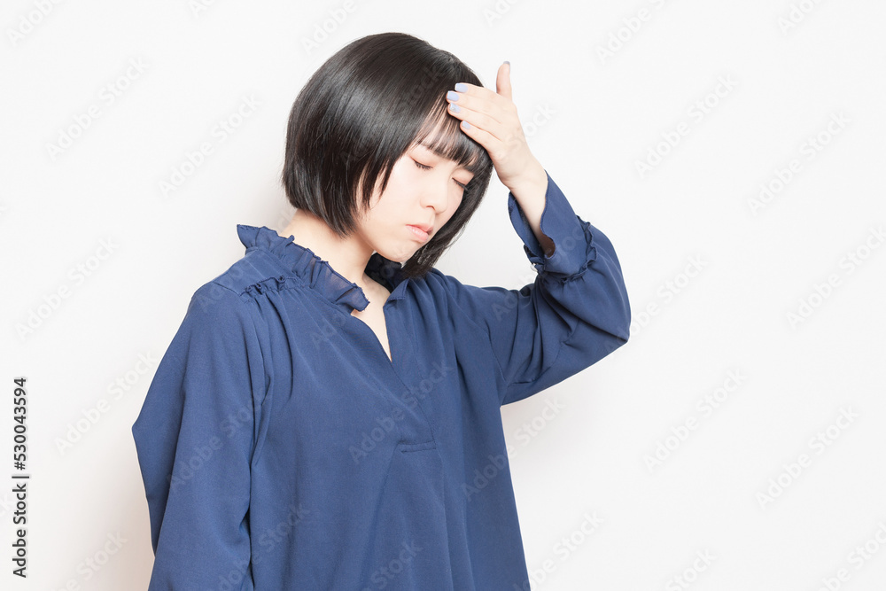 頭痛で痛む頭に手を当てている若い女性 頭痛で痛む頭に手を当てている若い女性