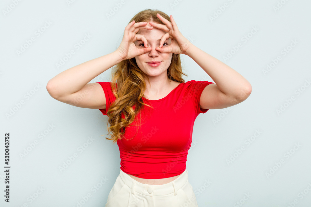 Young caucasian woman isolated on blue background showing okay sign over eyes Young caucasian woman isolated on blue background showing okay sign over eyes