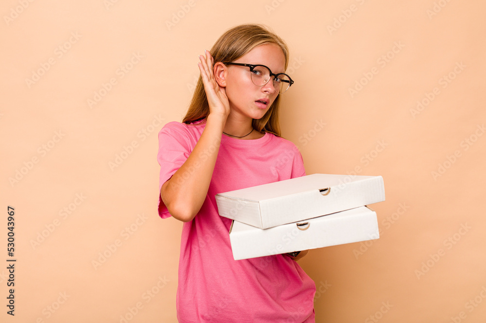 Little caucasian girl holding pizza isolated on beige background trying to listening a gossip. Little caucasian girl holding pizza isolated on beige background trying to listening a gossip.