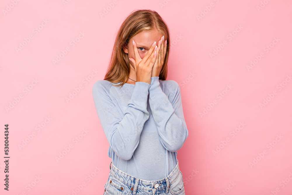 Caucasian teen girl isolated on pink background blink through fingers frightened and nervous. Caucasian teen girl isolated on pink background blink through fingers frightened and nervous.