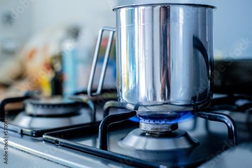 A pot stands on a gas stove. The gas glows blue. photo