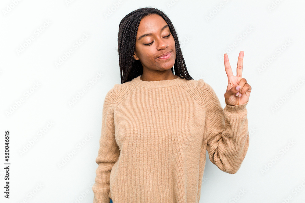 Young African American woman isolated on white background joyful and carefree showing a peace symbol with fingers. Young African American woman isolated on white background joyful and carefree showing a peace symbol with fingers.