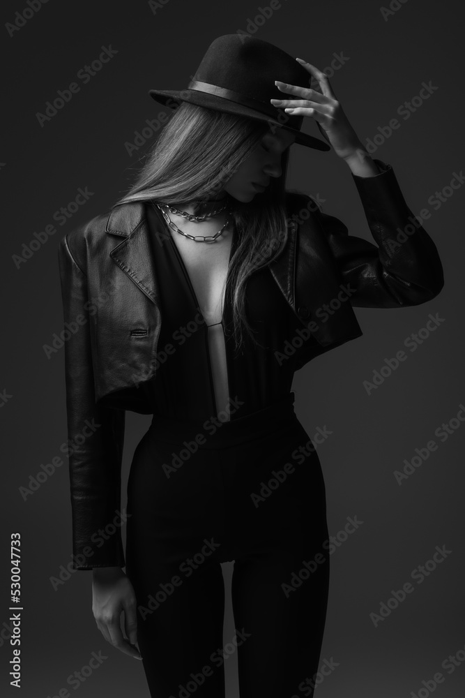Obraz premium monochrome photo of teenage model adjusting fedora hat in studio.