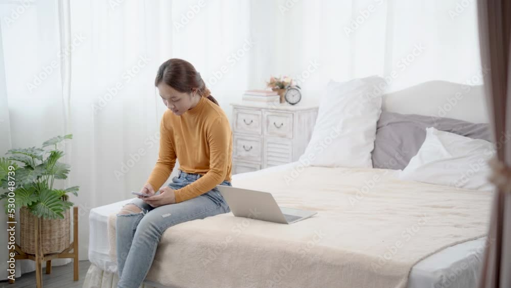 Asian woman sitting on bed using smartphone chatting with bestfriend, young girl takes a break from working with laptop to play on mobile phone. free time after work.
Asian woman sitting on bed using smartphone chatting with bestfriend, young girl takes a break from working with laptop to play on mobile phone. free time after work.