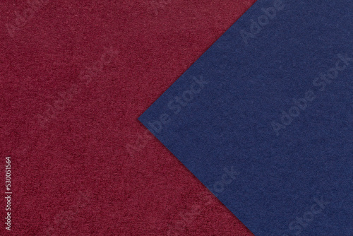 Texture of dark red paper background, half two colors with navy blue arrow, macro. Craft wine cardboard.