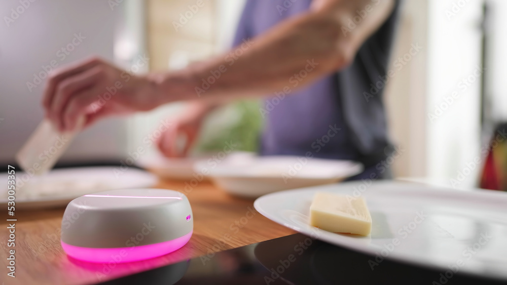 Empty light base hologram with person in background cooking in kitchen Empty light base hologram with person in background cooking in kitchen