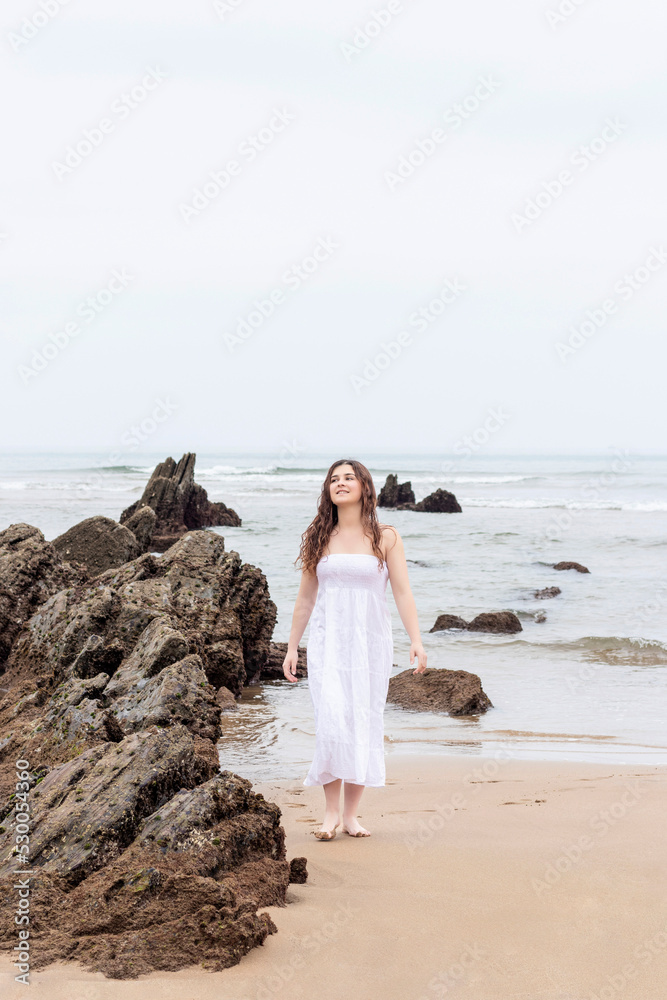 young brunette woman in white dress walking happily on the beach young brunette woman in white dress walking happily on the beach
