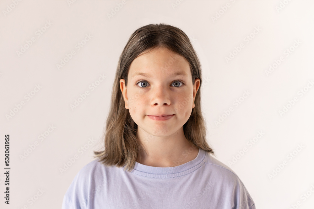 Portrait of curious preteen girl looking at camera. Funny little kid wearing blue T-shirt posing against white background. Curiosity concept Portrait of curious preteen girl looking at camera. Funny little kid wearing blue T-shirt posing against white background. Curiosity concept