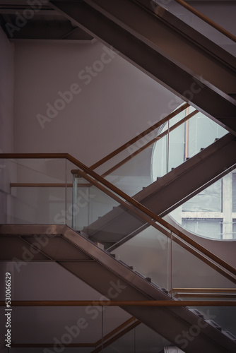 Side view of metal and glass stairs inside the building with sunlight shine through round window glass. Emergency exit by a stairwell in a Modern building. Selective Focus.