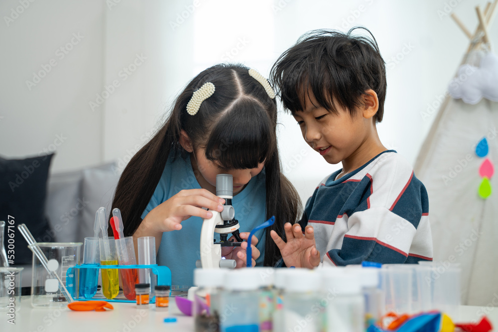 Two little scientists making chemical test with microscope in living room. Two little scientists making chemical test with microscope in living room.
