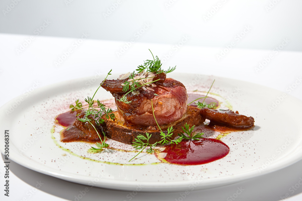Baked camembert in parma ham on brioche with berry jam. Elegant food - hot appetizer of camembert and ham in summer menu. Cheese appetizer in fine dining. Summer menu.