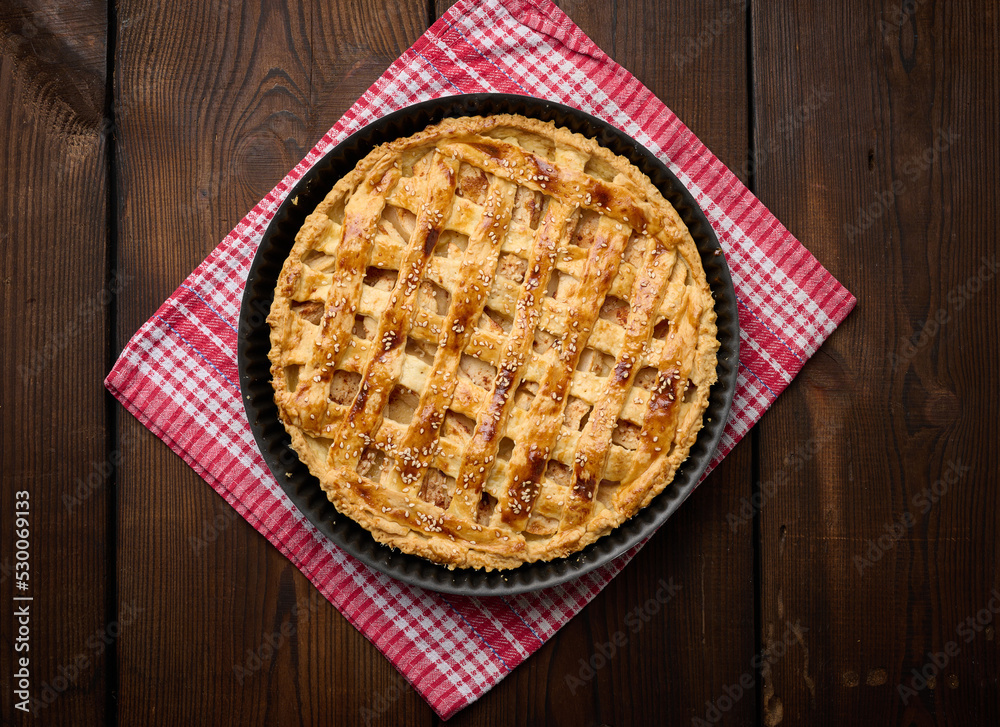 Round baked apple pie on a brown wooden table, top view Round baked apple pie on a brown wooden table, top view