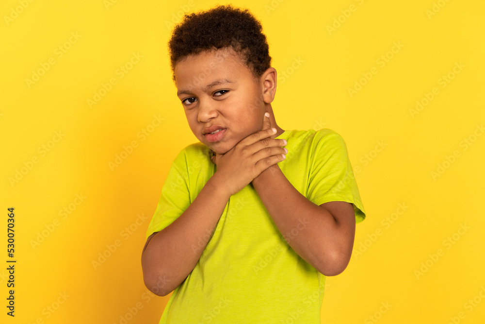 Portrait of unwell preteen boy suffering from sore throat. Mixed race child wearing green T-shirt touching his neck. Childs health problems concept Portrait of unwell preteen boy suffering from sore throat. Mixed race child wearing green T-shirt touching his neck. Childs health problems concept