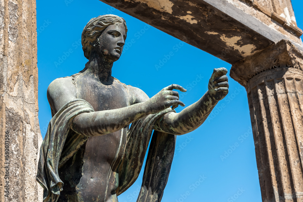 Detail of ancient metal statue situated in Pompeii representing a young man trying to hold something in the air