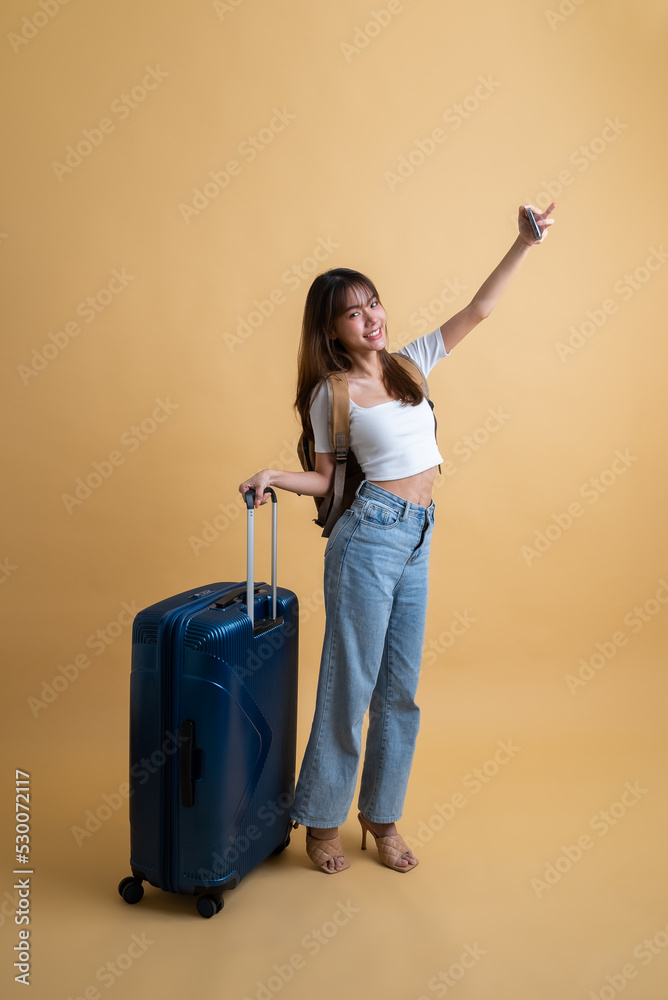 Full length of young attractive Asian woman traveler in casual clothes with backpack and luggage doing selfie shot on mobile phone, Tourist girl having cheerful holiday trip concept Full length of young attractive Asian woman traveler in casual clothes with backpack and luggage doing selfie shot on mobile phone, Tourist girl having cheerful holiday trip concept
