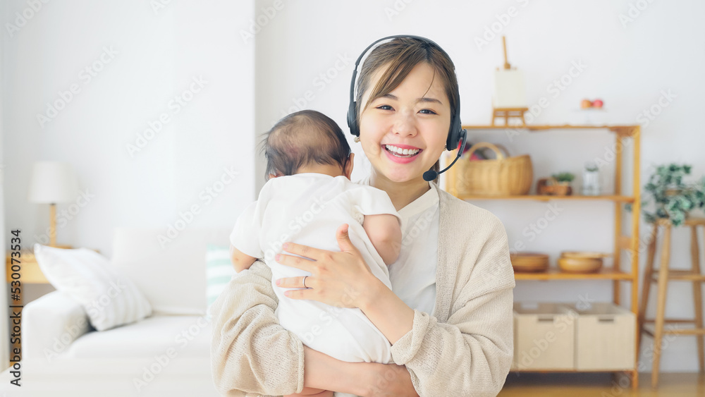 赤ちゃんを抱っこしながらビデオ通話で話す女性
