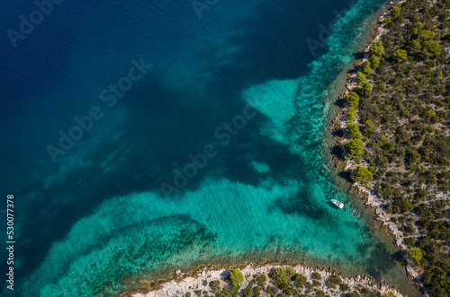 Aerial shot above beautiful turquoise water harbor with a white yacht near small island in Adriatic sea near from Sibenik city  Dalmatia in Croatia. Nature  environment concept.