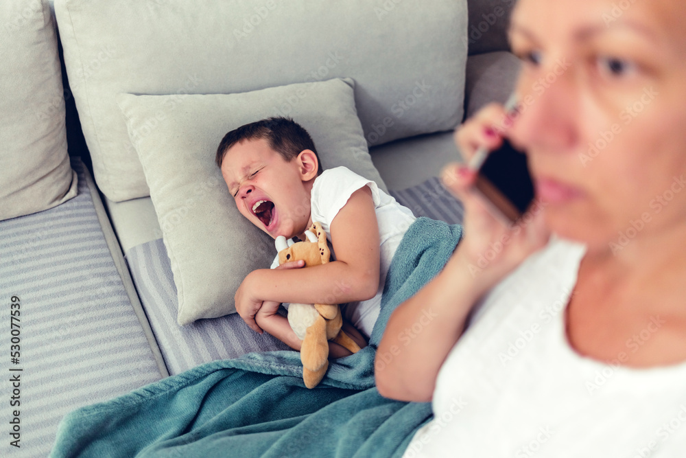 Sick boy lying in bed and mother hand taking temperature. Mother