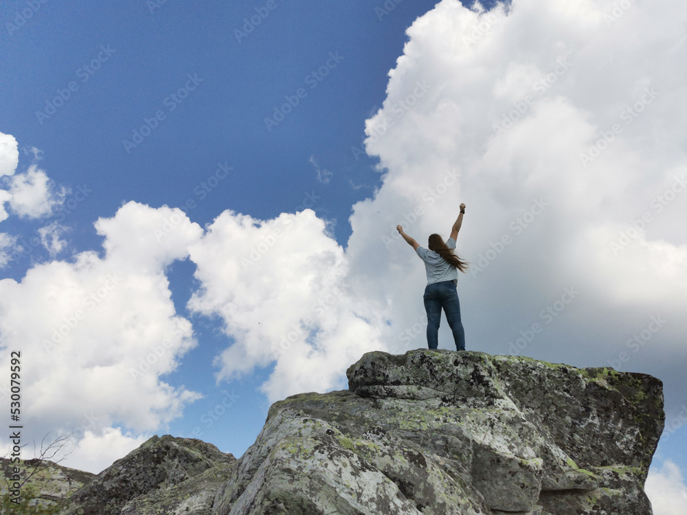 Hiker woman arms raised in the sky on mountain top summit above the clouds Hiker woman arms raised in the sky on mountain top summit above the clouds