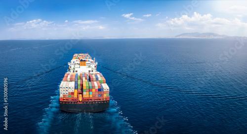 Panoramic back view of a cargo ship carrying containers for import and export, business logistic and transportation in open sea with copy space  photo