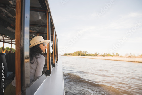 Mujer viajera con sobrero navegando en barco por el rio © Juan