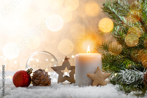 Christmas candle on snow-covered boards - decoration with natural elements, twigs, pine cones, Christmas decorations.
