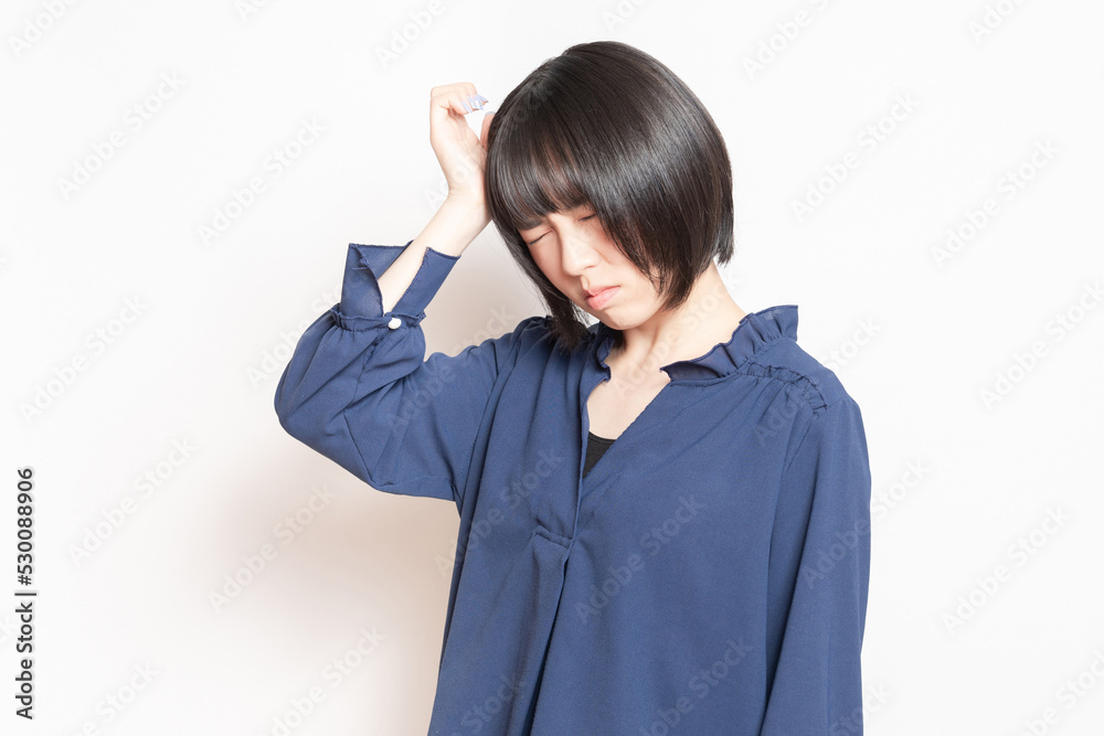 白バックの前に立って、困っている若い女性