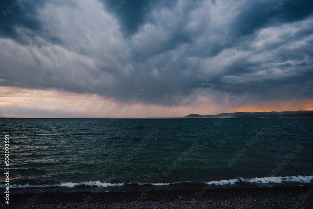 Sunset on Ugii lake in Mongolia on stormy day with big dark clouds in the sky Sunset on Ugii lake in Mongolia on stormy day with big dark clouds in the sky