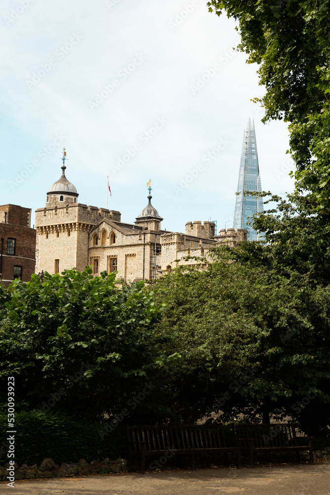 the tower of London view from a nearb park with trees in front and the Shard in the back vertical