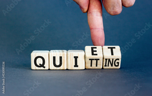 Quiet quitting symbol. Concept words Quiet quitting on wooden cubes. Businessman hand. Beautiful grey table grey background. Business quiet quitting concept. Copy space. photo