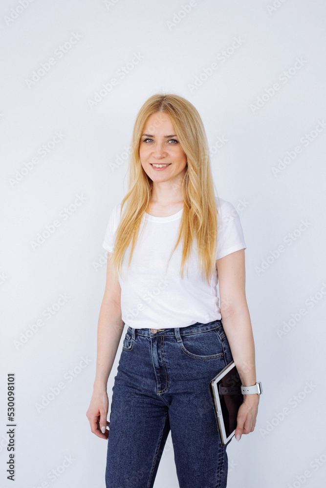 Obraz premium Young woman holding a tablet in her hands on a light background