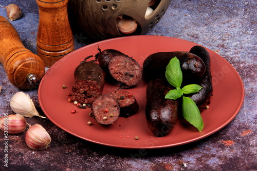 Baked blood sausage on a red plate decorated with red cranberries, Traditional Latvian blood sausages photo