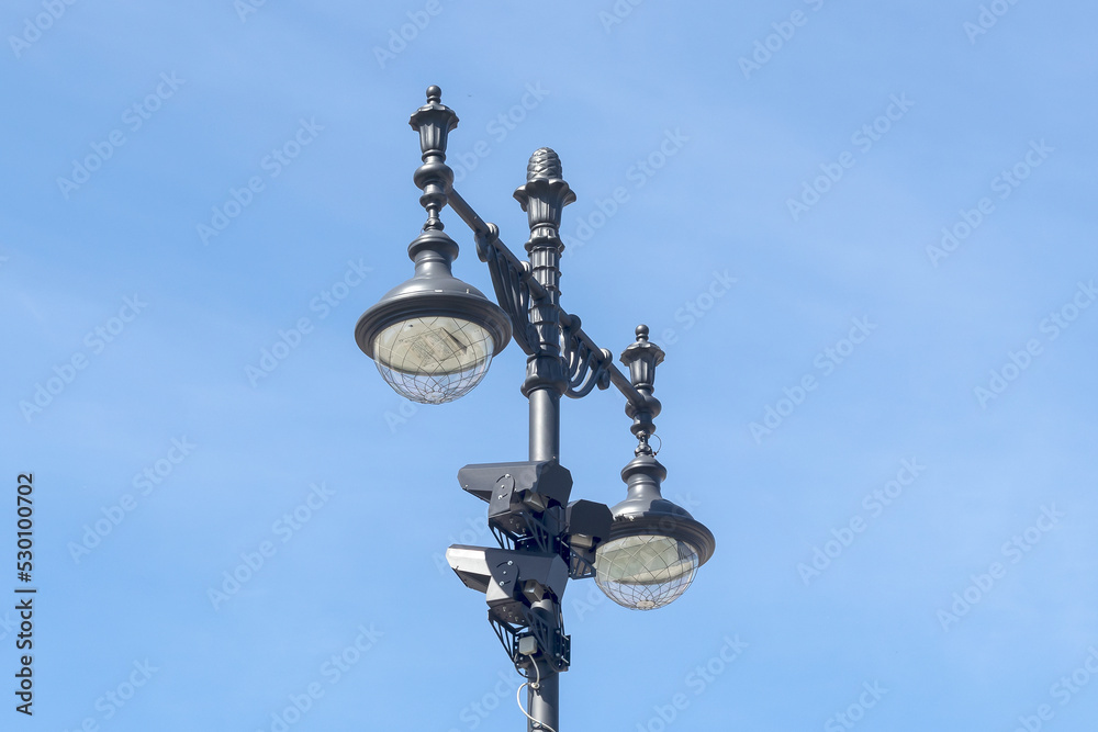 Pillar with night city lighting lamps and CCTV cameras.