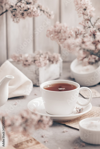 Cup of tea and lilac flowers on wooden table.