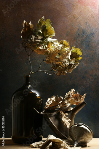 Composizione verticale con bottiglia, imbuti, foglie di quercia; still life su fondo scuro