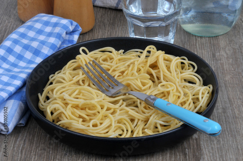 Assiette de spaghettis avec une fourchette et un verre d'eau en gros plan