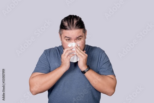 A man blows his nose into a tissue paper. Dealing with a cold, rhinitis or allergy. photo