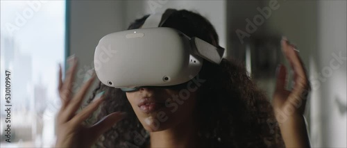 DOLLY IN Attractive African American female puts on a VR virtual reality metaverse headset at home