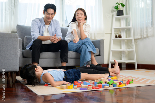 Asian family with children playing and building tower of colorful wooden toy blocks in living room at home, Educational game.