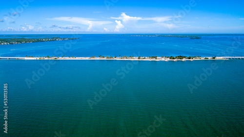 Aerial View of the Causeway Bridge Before Hurricane Ian in Sanibel, Florida with the Bay and a Preserve in the Foreground and the Gulf of Mexico in the Background Featuring a Blue Sky and Blue Water