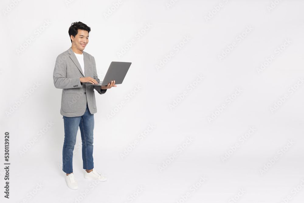 Happy young Asian business man using laptop computer and standing isolated on white background, Full body composition