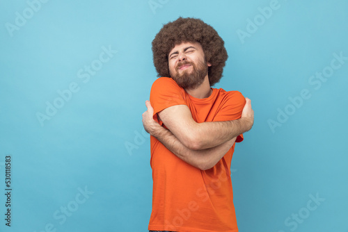 Canvas Print Portrait of selfish narcissistic man with Afro hairstyle embracing himself and smiling with expression of great ego, pleasure and self-esteem