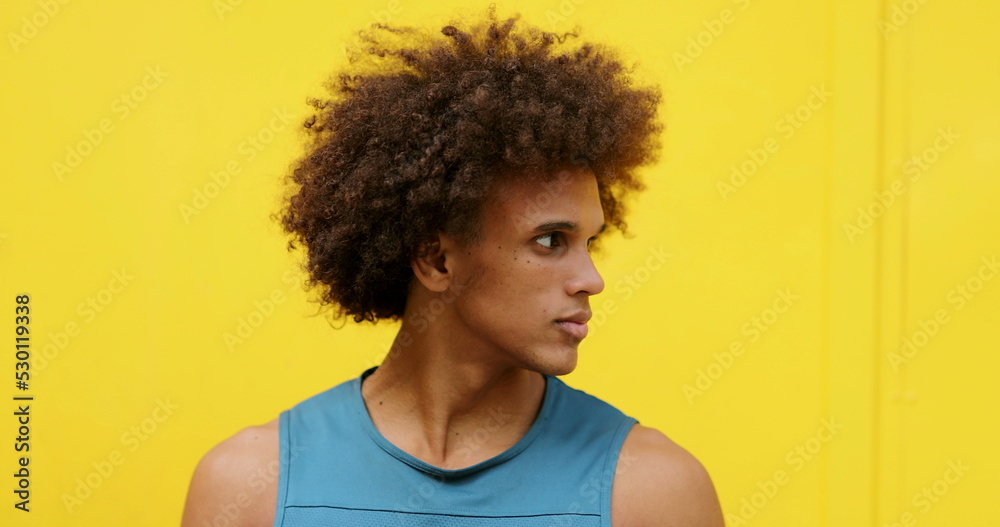 Handsome mixed race young black man looking to camera with yellow background Handsome mixed race young black man looking to camera with yellow background