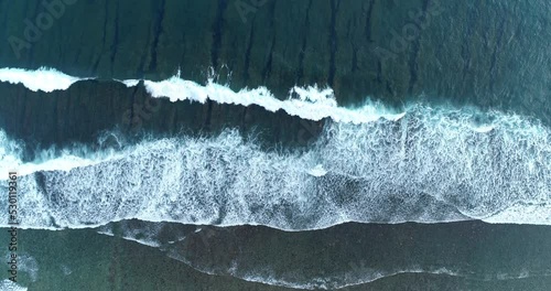 Aerial top down view deep blue ocean waves crashing and foaming on the shore. 4K