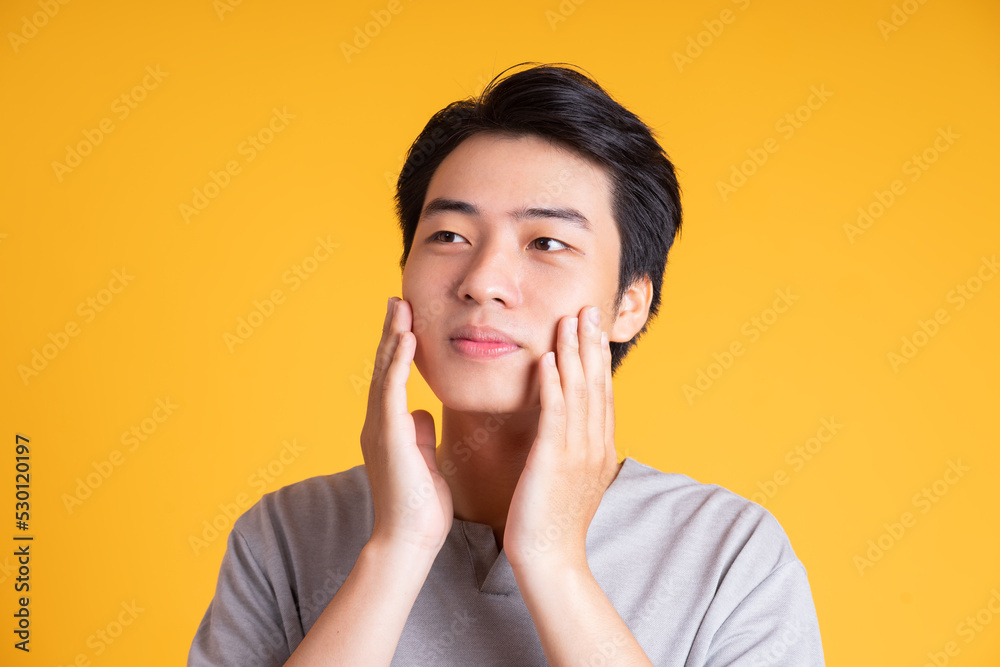 Asian young man posing on a yellow background Asian young man posing on a yellow background