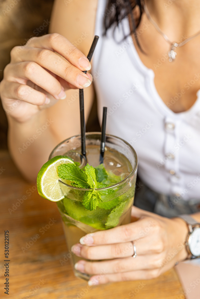 Fototapeta premium The girl tastes a cocktail at the restaurant bar 