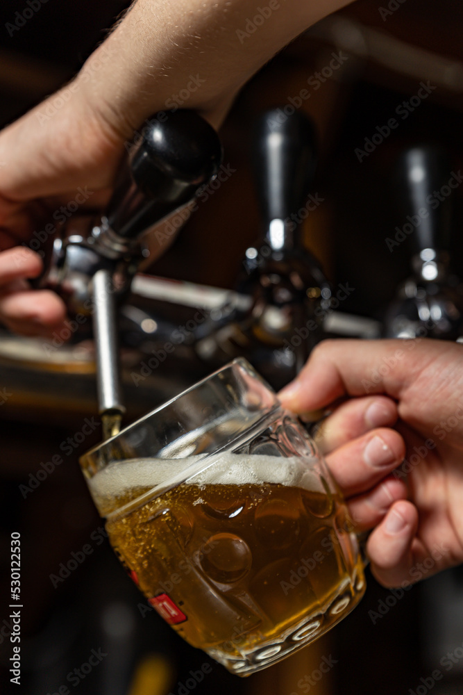 bartender pours beer into a glass at the restaurant bar
