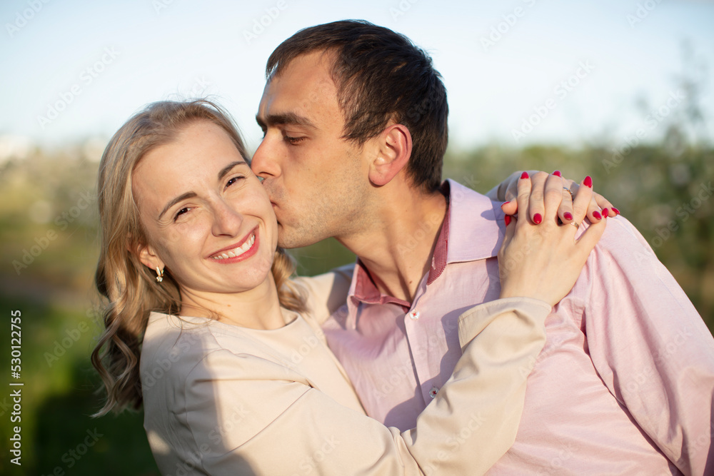Young happy couple in love outdoors. loving man and woman on a walk in a spring blooming park Young happy couple in love outdoors. loving man and woman on a walk in a spring blooming park