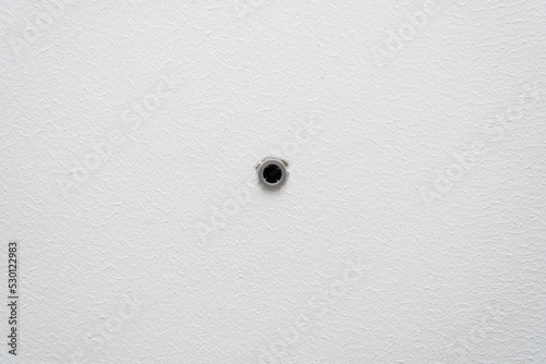 Hole in white painted wall made by drill with inserted dowel.