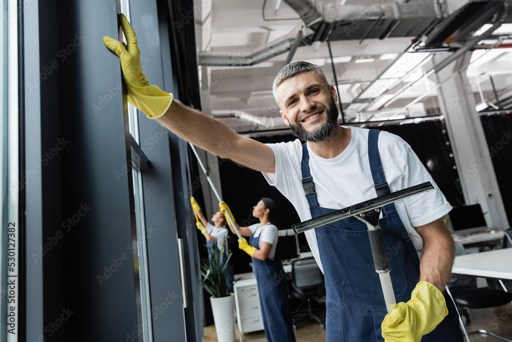 custom made wallpaper toronto digitalhappy bearded man with window wiper smiling at camera near multiethnic women on blurred background.